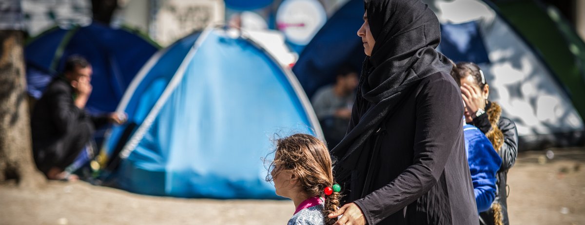 Flüchtlinge unterstützen Mutter und Töchter vor Flüchtlingszelten