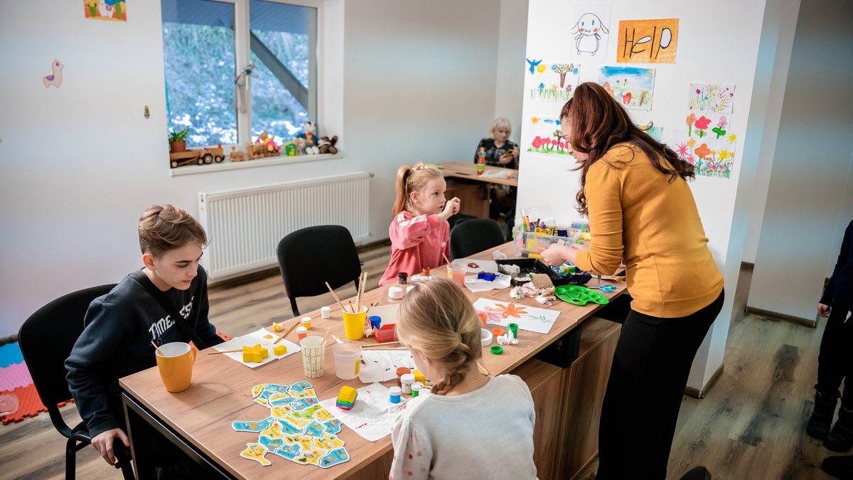 Ukrainische Kinder basteln gemeinsam an einem Tisch