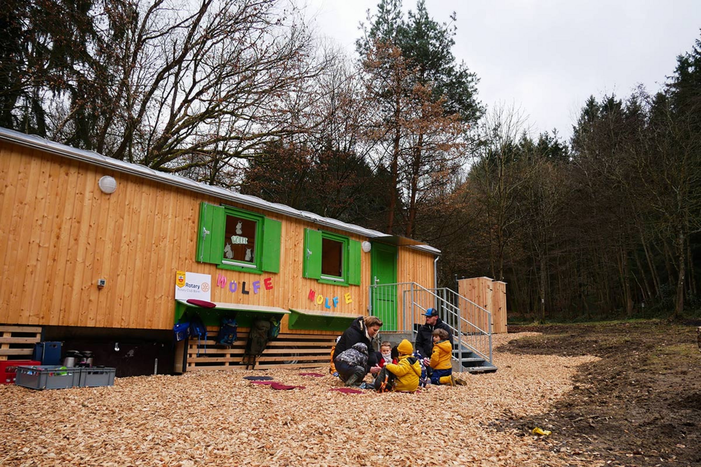 Kindergartenkinder und Betreuer vor dem Waldkindergartenwagen