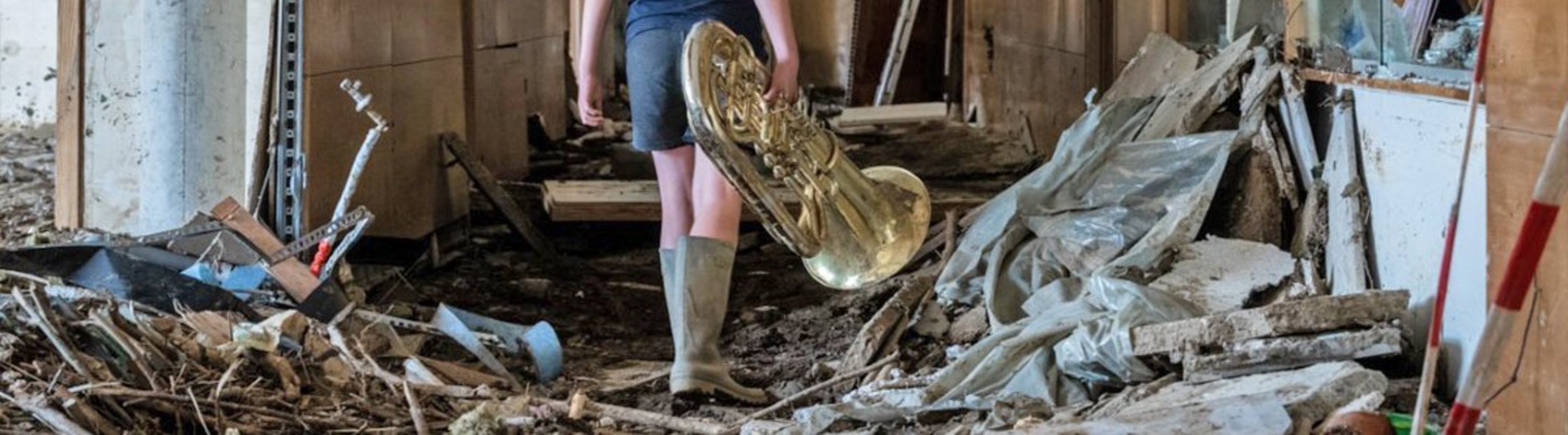 Ein Junge mit einem geretteten Musikinstrument: Das Hochwasser hat im Peter-Joerres-Gymnasium in Bad Neuenahr großen Schaden angerichtet.