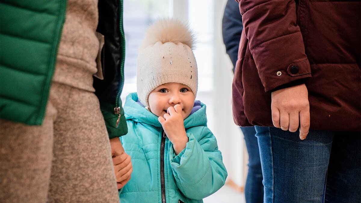 Ein ukrainisches Mädchen mit Wollmütze schaut schüchtern in die Kamera