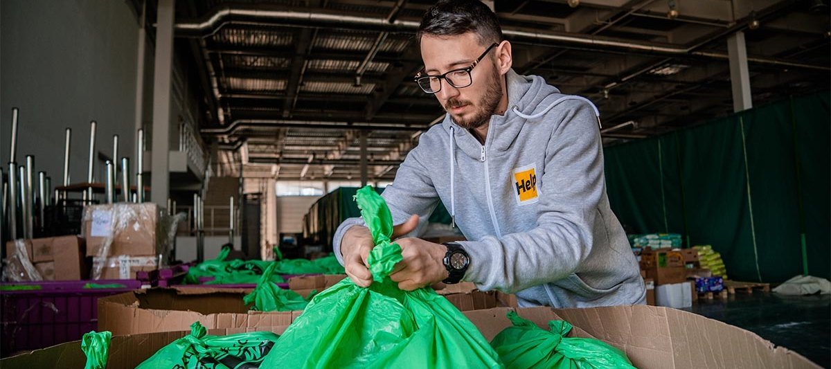 Ein Help-Mitarbeiter packt Tüten mit Hilfsgütern