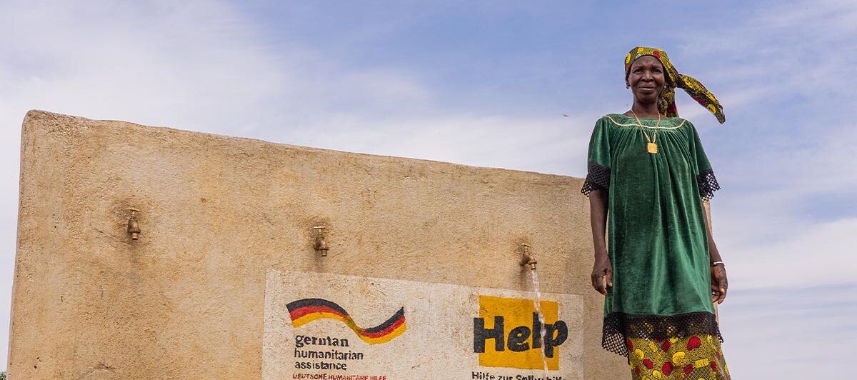 Eine Frau steht vor einem Brunnen in Mali, den Help errichtet hat