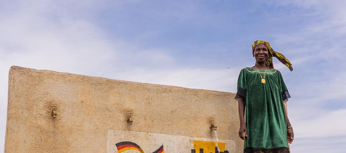 Eine Frau steht vor einem Brunnen in Mali, den Help errichtet hat
