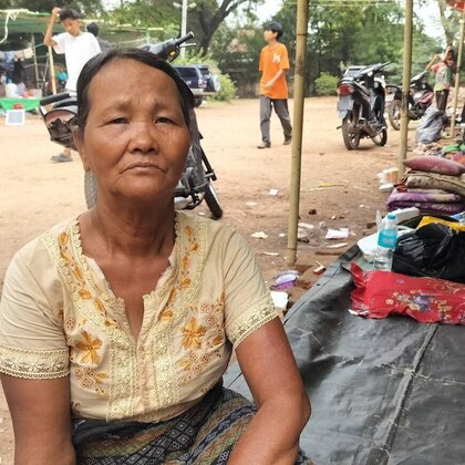 Daw Hla Aye aus Myanmar sitzt auf einer Zeltplane