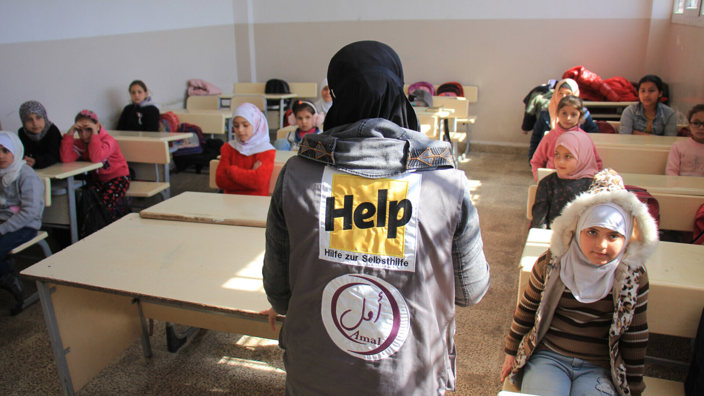 Humanitäre Helferin steht in einer Schulklasse