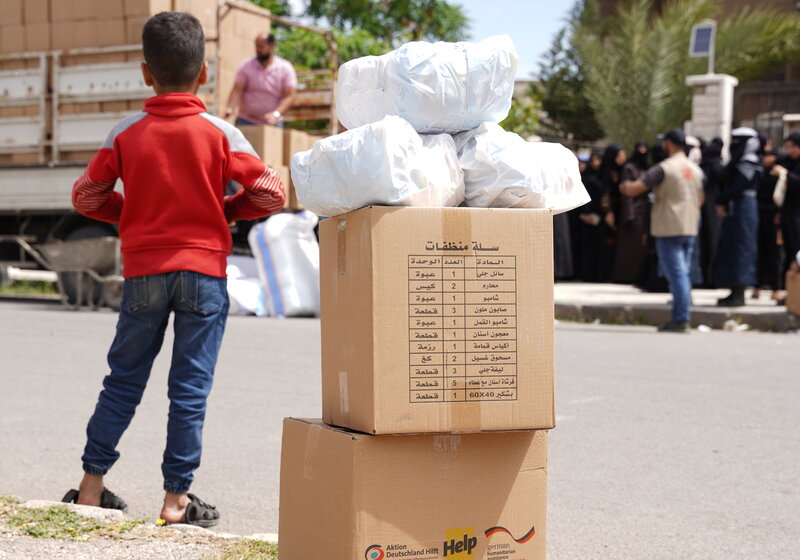 Ein syrischer Junge steht neben Hilfspaketen