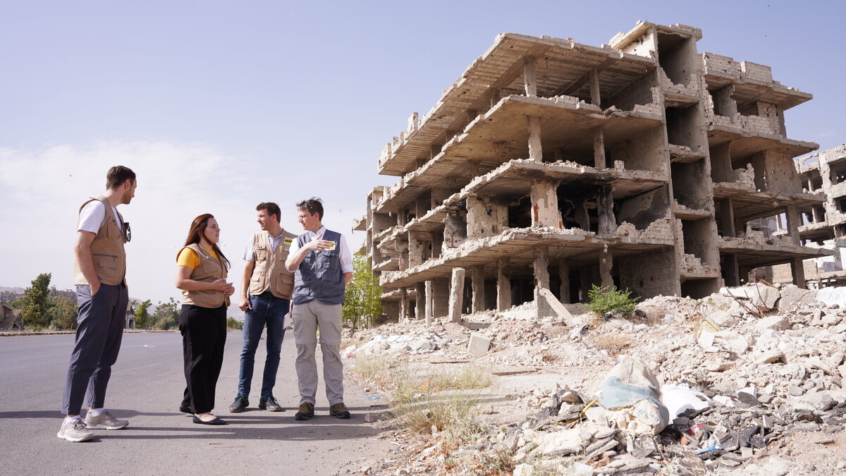 Help delegation in front of a destroyed neighbourhood in Damascus, Syria