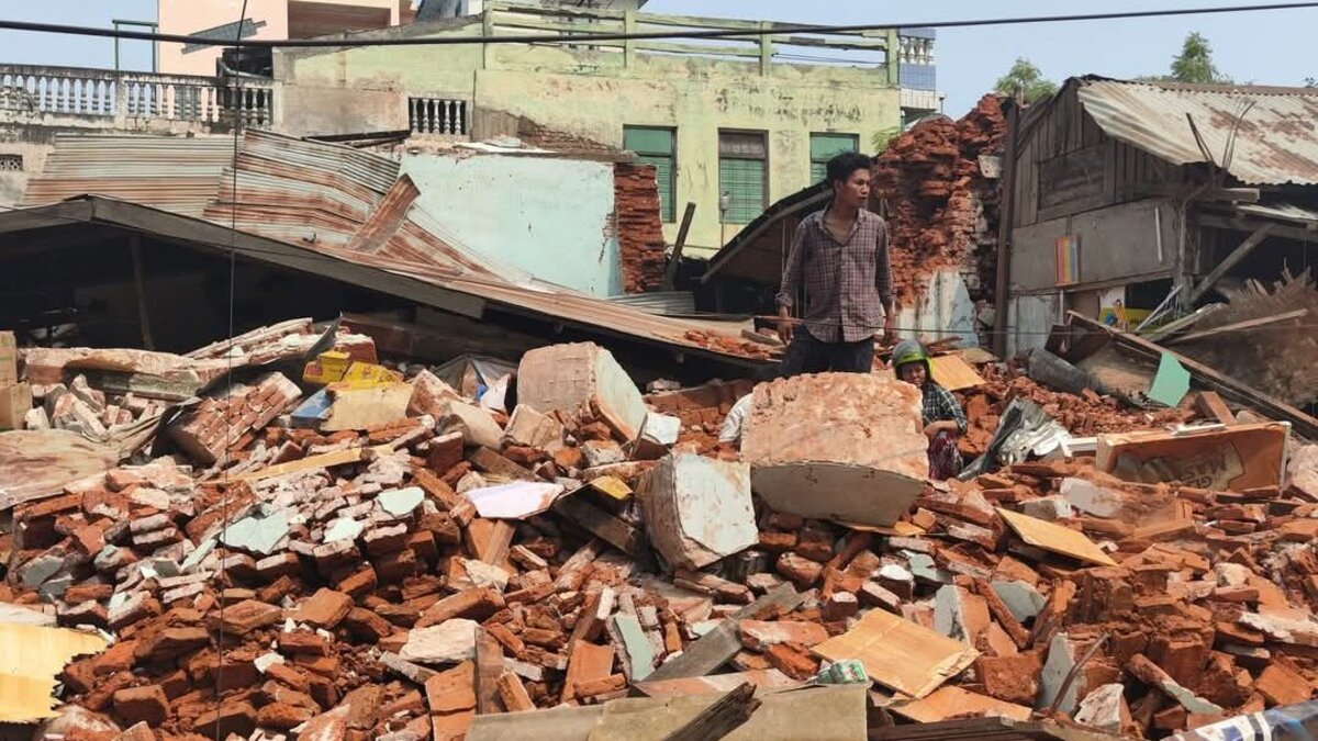 A man stands in the rubble of a house in Myanmar