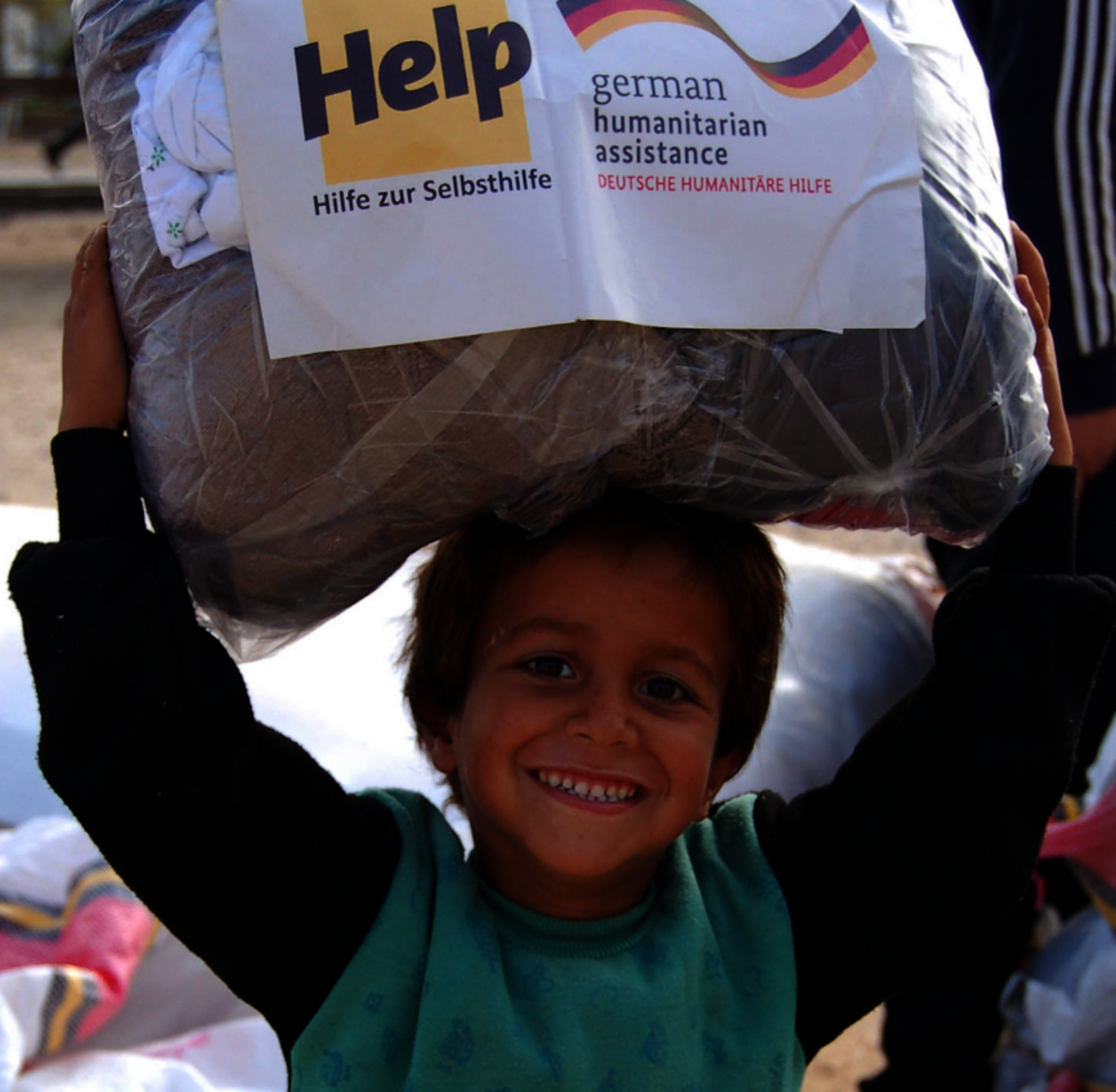 A Syrian boy receives a parcel with winter clothes