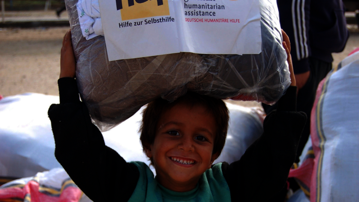 Ein syrischer Junge erhält ein Paket mit Winterkleidung