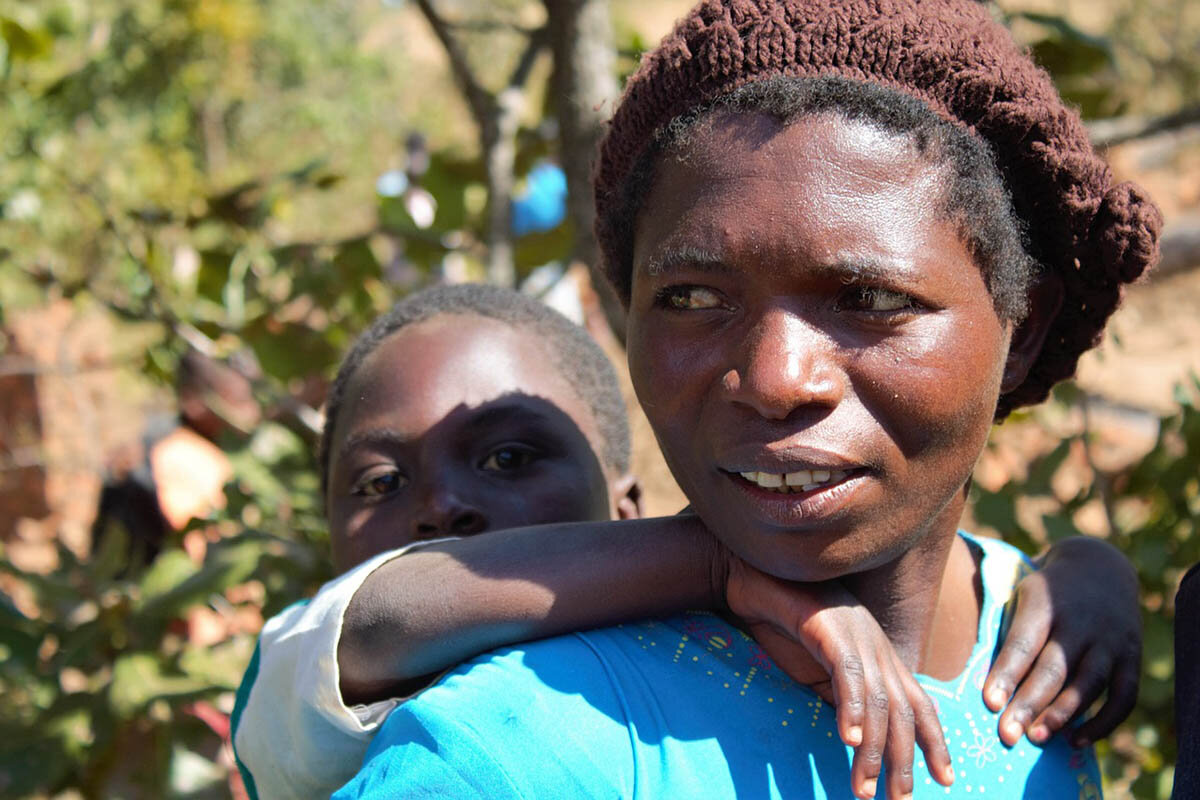 Eine junge Frau in Malawi mit ihrem Kind auf dem Rücken