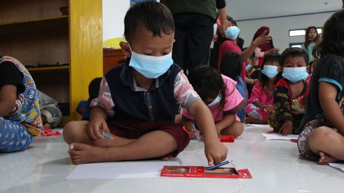 Kleine Kinder sitzen in einer Halle und malen