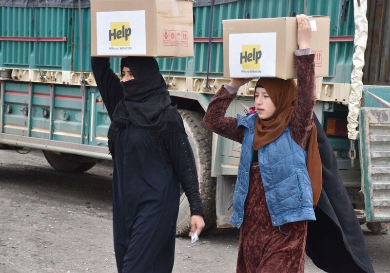 Zwei syrische Frauen mit Hilfspaketen von Help