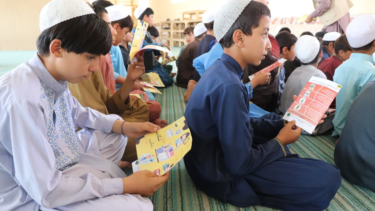 Afghanische Kinder lesen sich Infoblätter zu Landminen durch