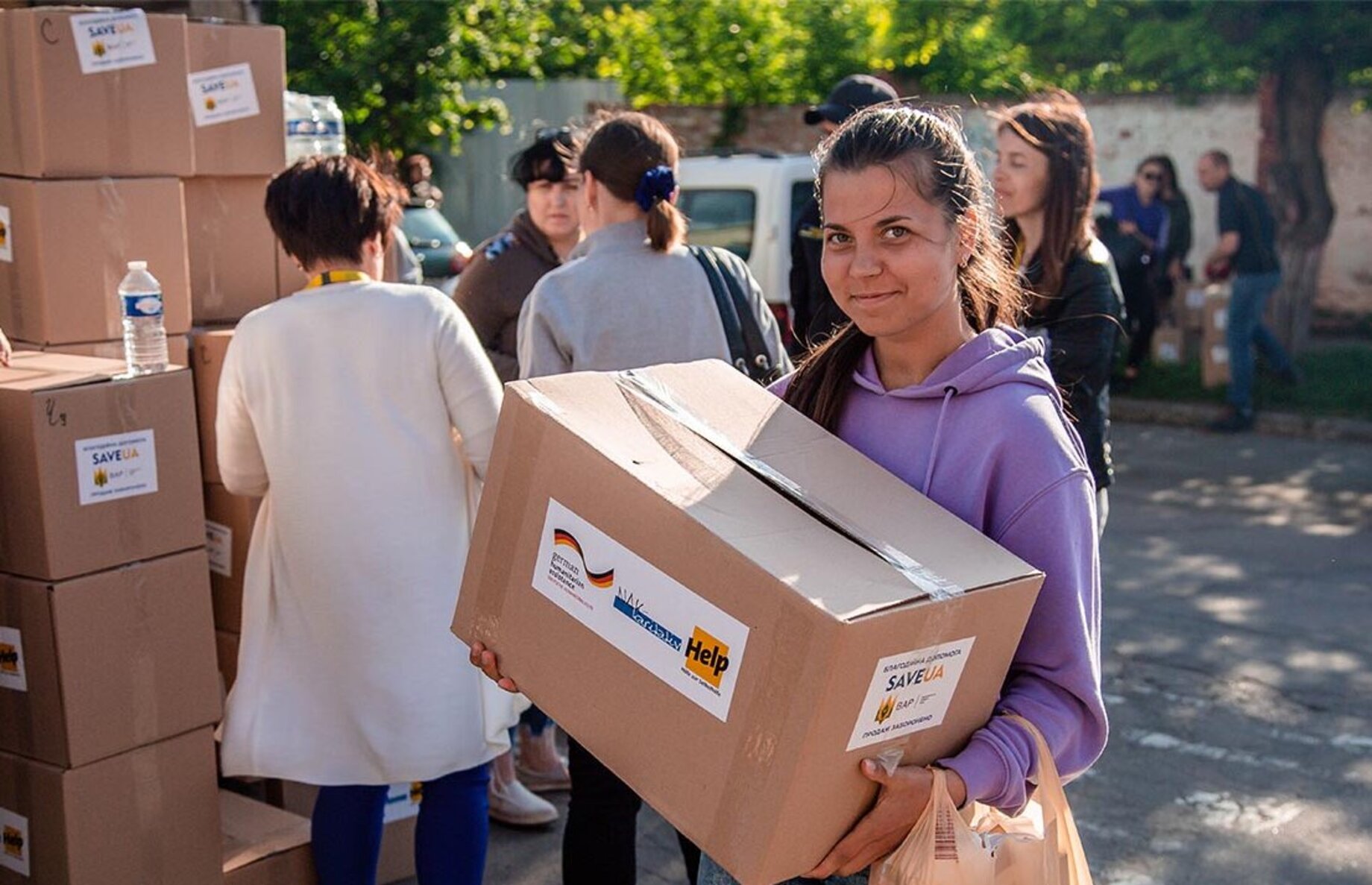 Eine junge Frau hält ein Hilfspaket von Help und lächelt