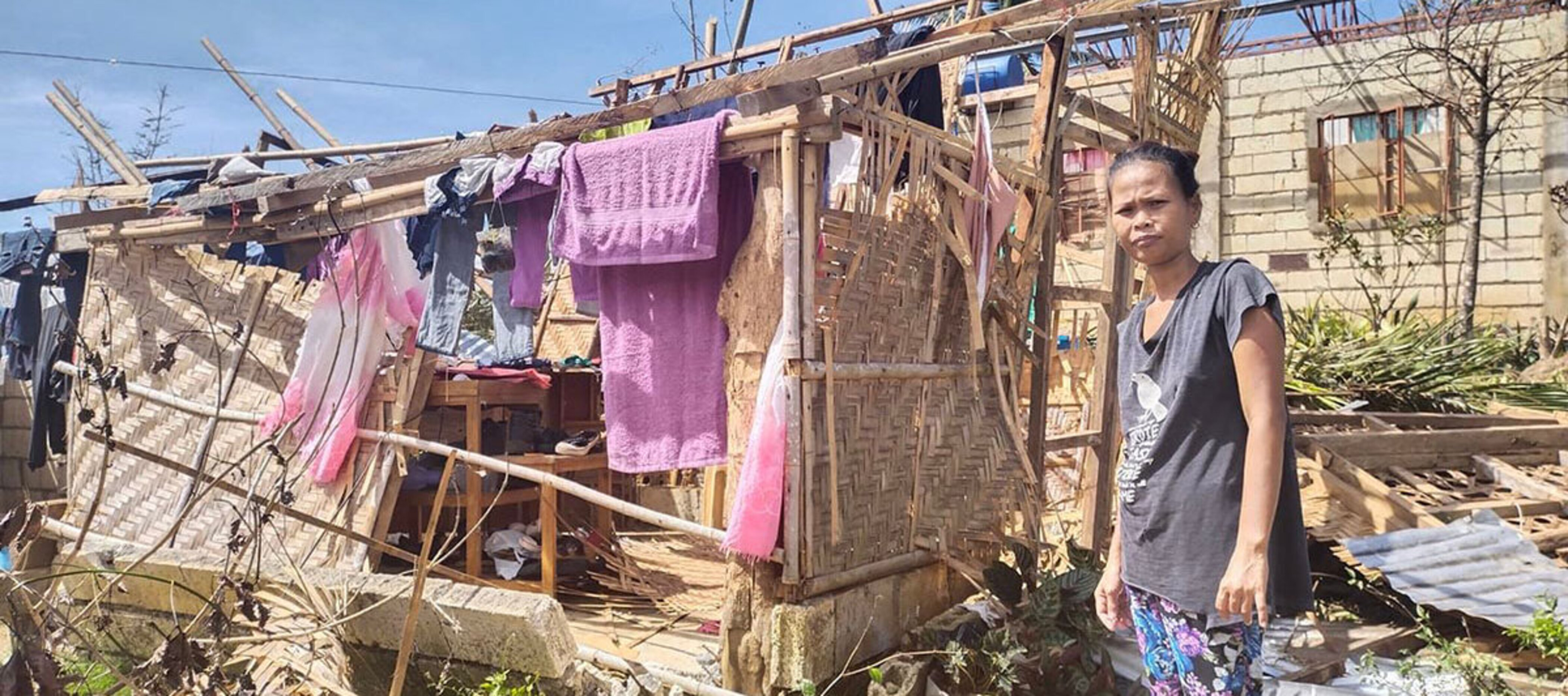 Eine Frau auf den Philippinen steht vor ihrem zerstörten Haus