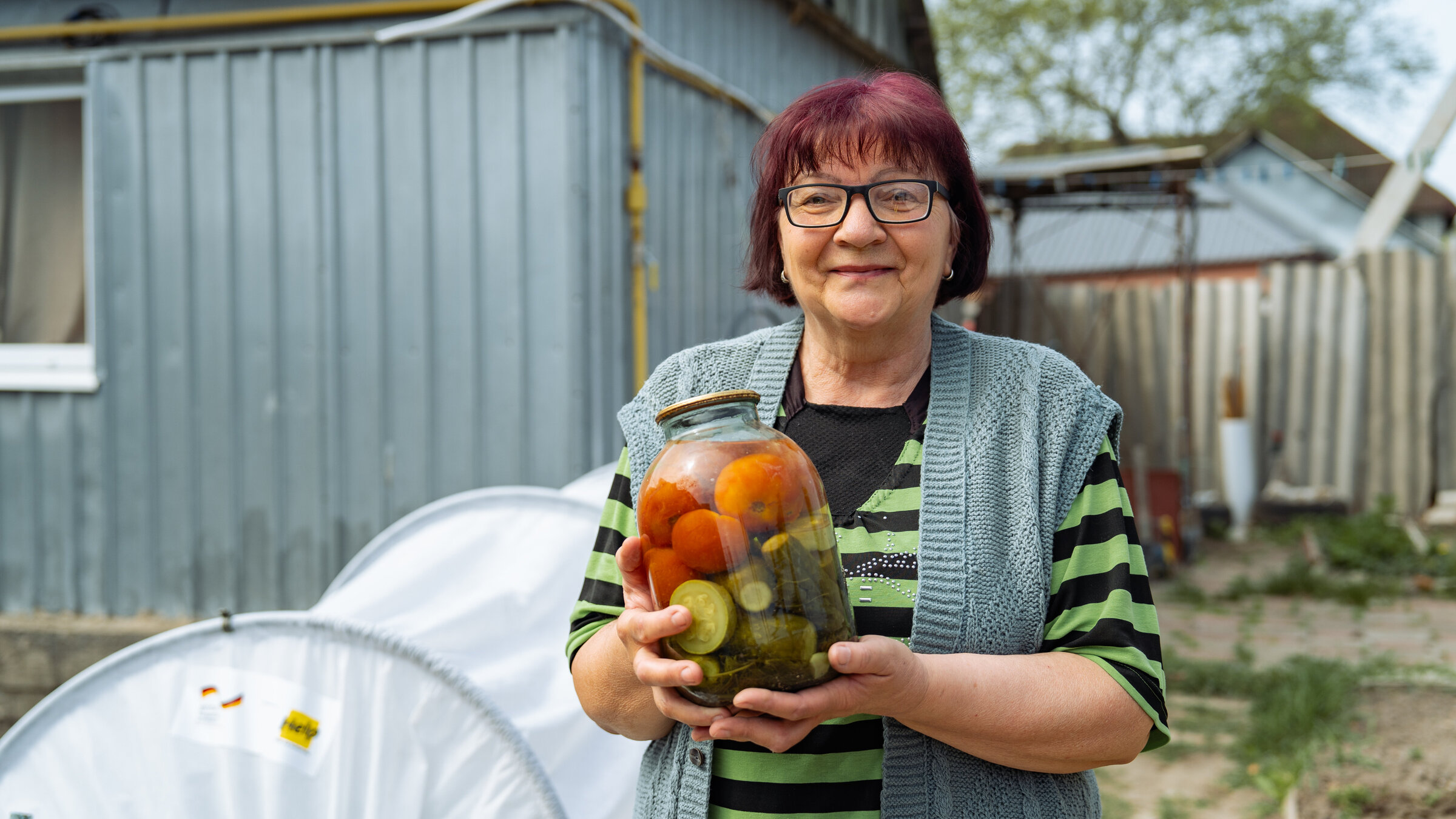 Eine ukrainische Frau hält ein Glas mit eingemachtem Gemüse