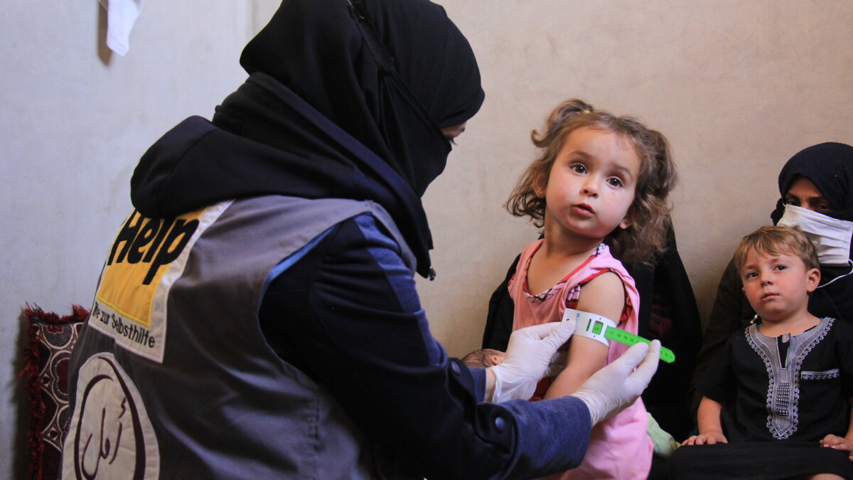 Eine Gesundheitsfachkraft misst den Oberarmumfang eines syrischen Mädchens