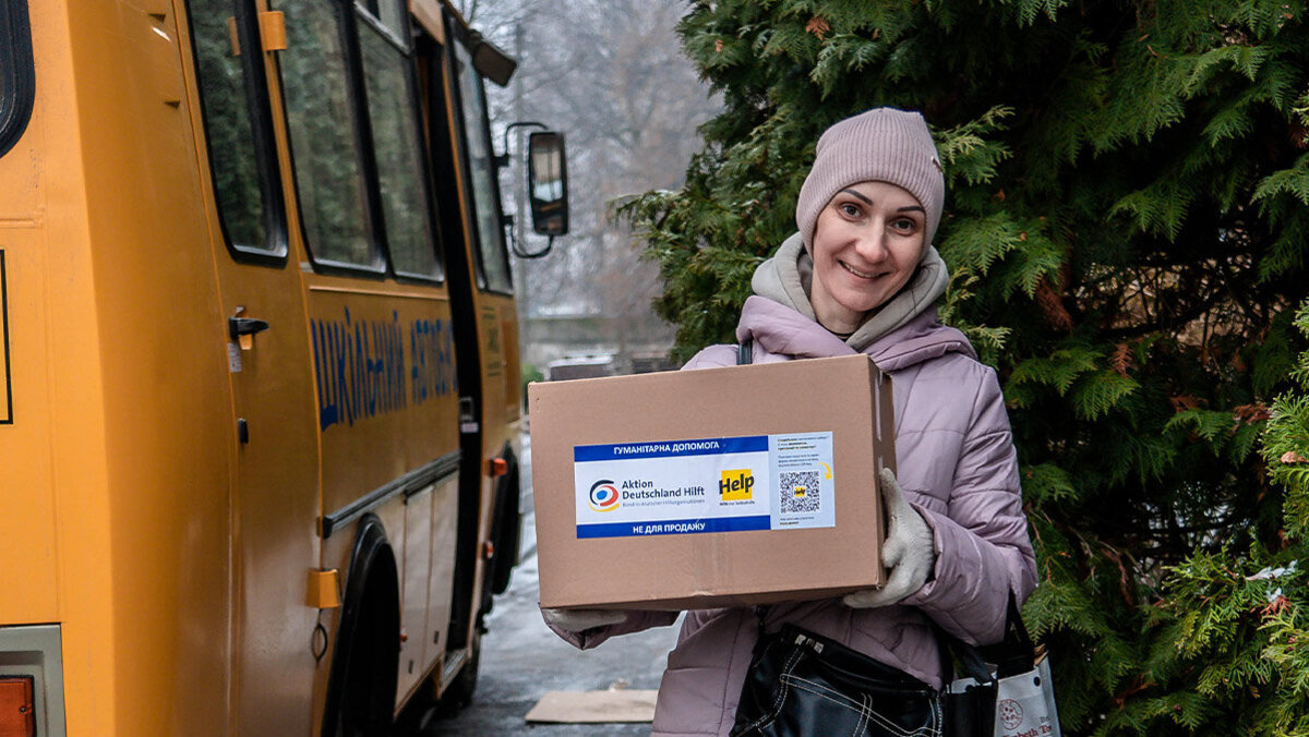 Eine lächelnde Ukrainerin mit einem Help-Hilfspaket