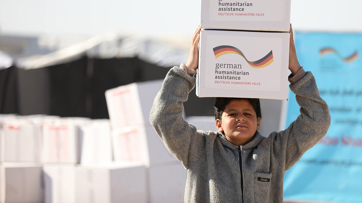 Humanitäre Hilfe: Petition gegen Einsparungen der künftigen Bundesregierung Ein syrischer Junge trägt zwei Hilfspakete mit der Aufschrift "German Humanitarian Assistance" auf seinem Kopf