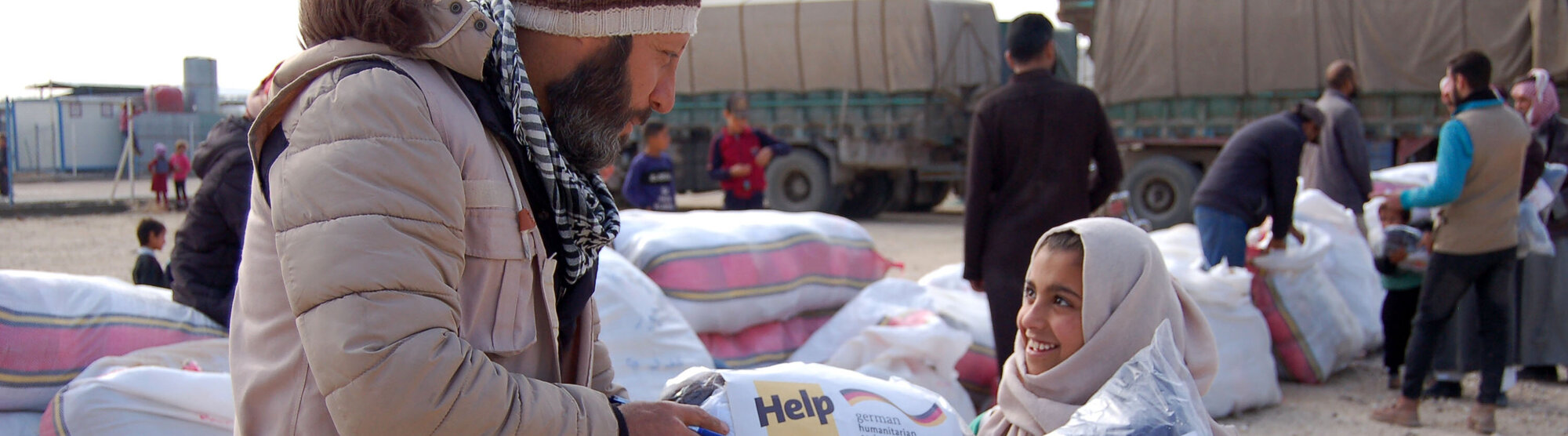 Humanitärer Helfer verteilt Winterkleidung an syrisches Kind
