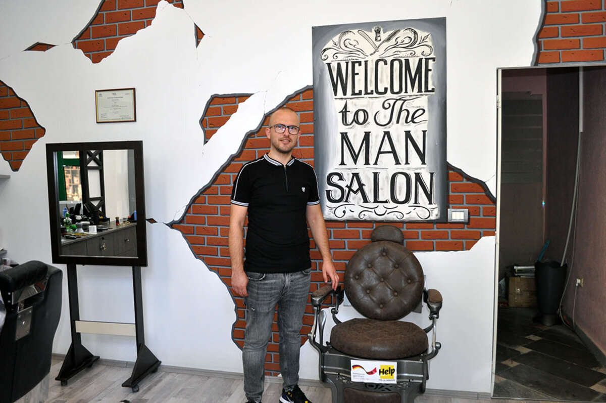 Friseur Skerdi steht in seinem Salon, den er dank Help eröffnen konnte.