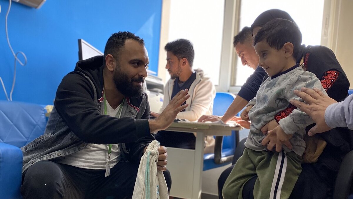 An aid worker in conversation with a Palestinian boy