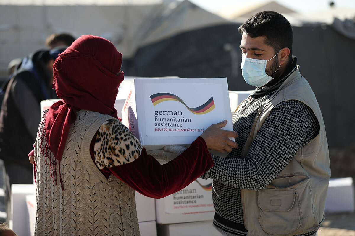 Ein Helfer verteilt Hilfsgüter an syrische Geflüchtete