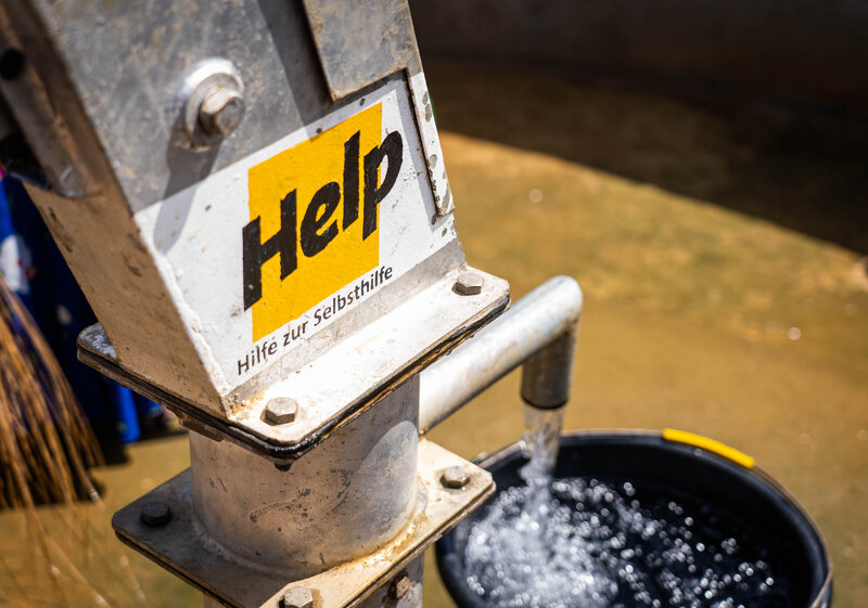Sauberes Wasser fließt aus einem Help-Brunnen