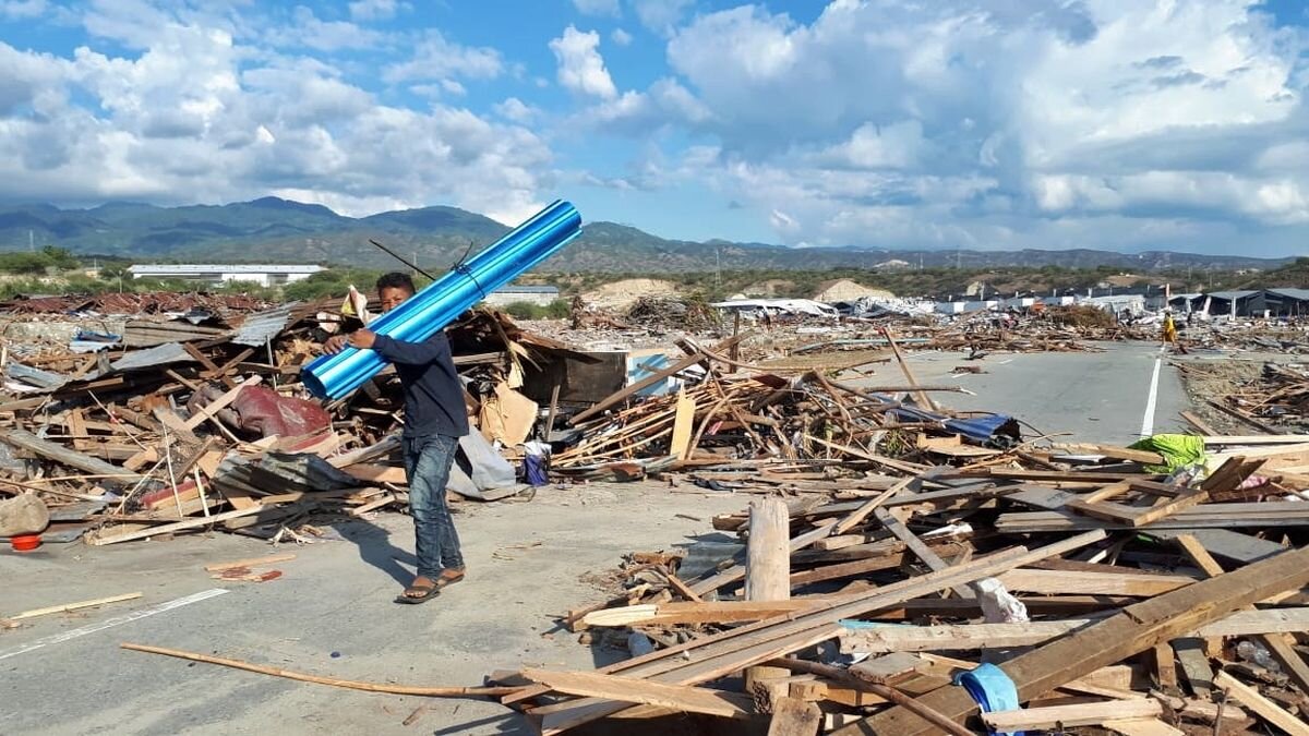 Indonesien spenden: Zerstörung nach dem Erdbeben Ein Mann läuft über eine vom Erdbeben zerstörte Straße auf einer indonesischen Insel