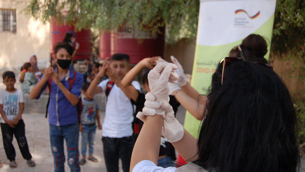 Humanitäre Helferin zeigt Kindern richtiges Händewaschen