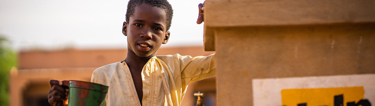 Ein Junge steht neben einem Help-Brunnen in Mali
