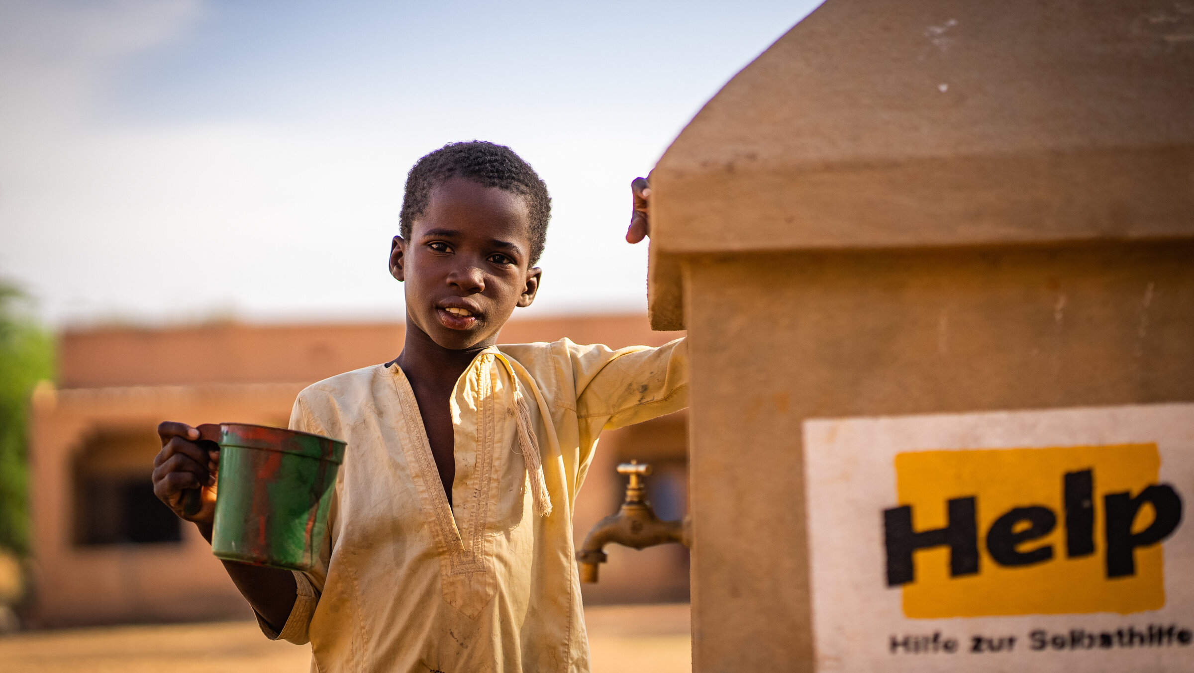 Ein Junge steht neben einem Help-Brunnen in Mali