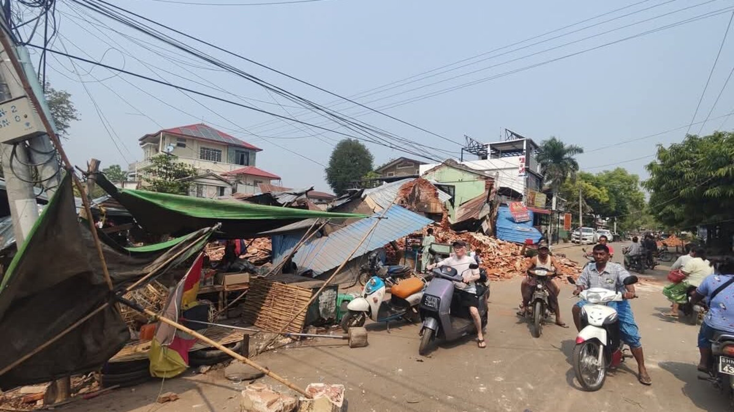People ride scooters through an earthquake-ravaged town in Myanmar