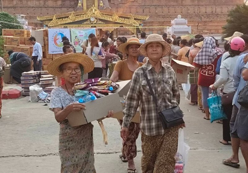 Drei myanmarische Frauen tragen Hilfsgüter
