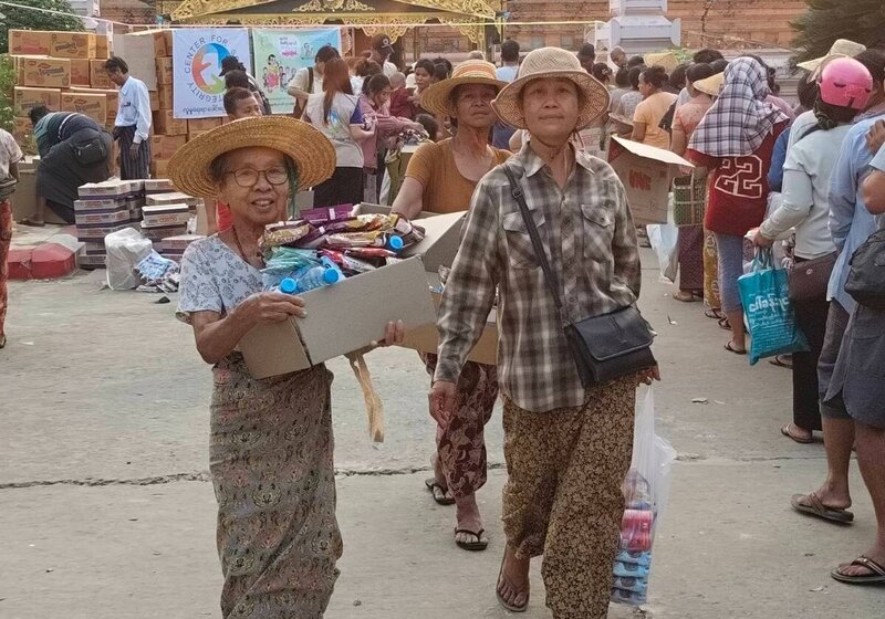 Drei myanmarische Frauen tragen Hilfsgüter