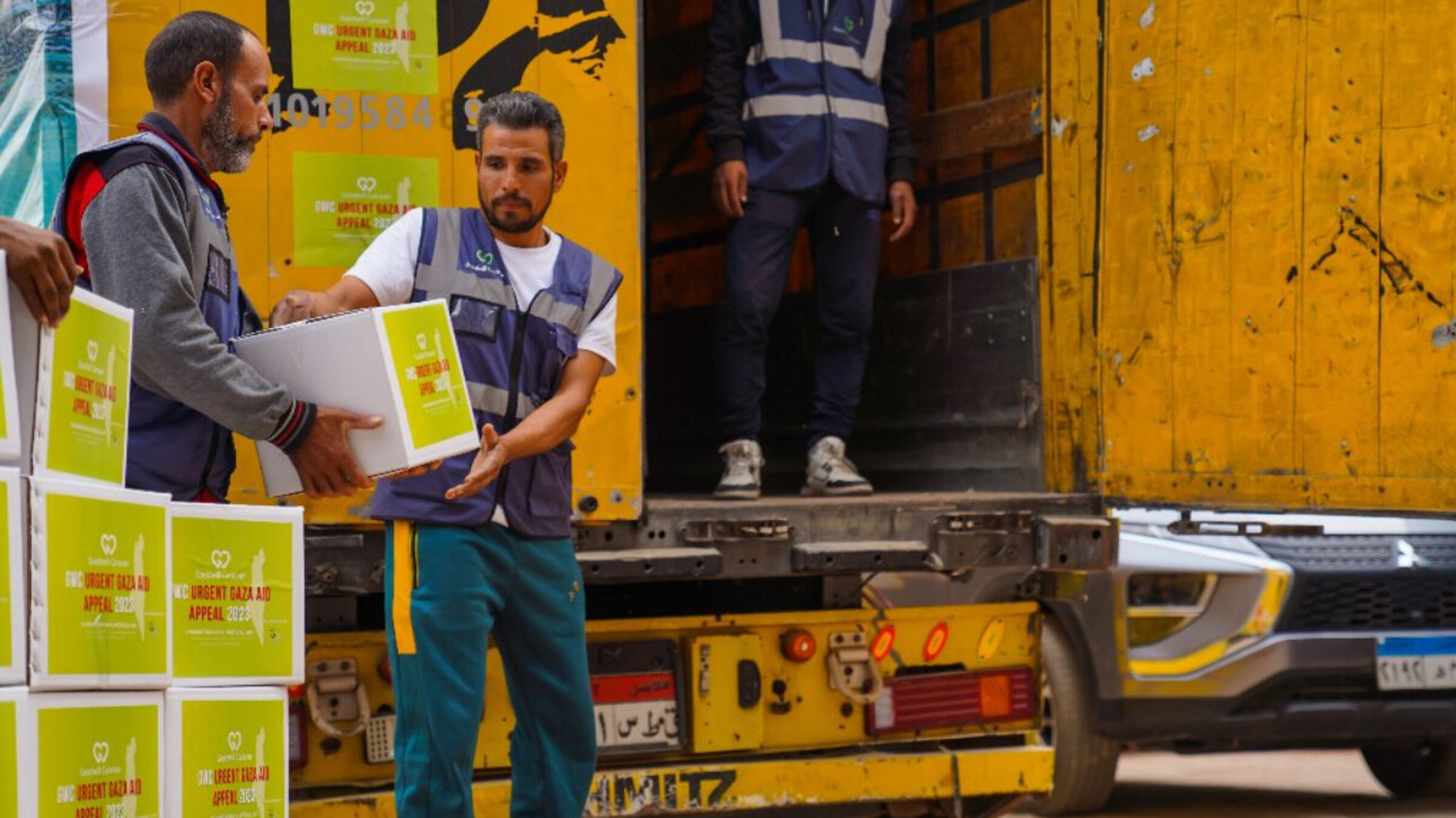 Drei Männer beladen einen Hilfstransport für Gaza