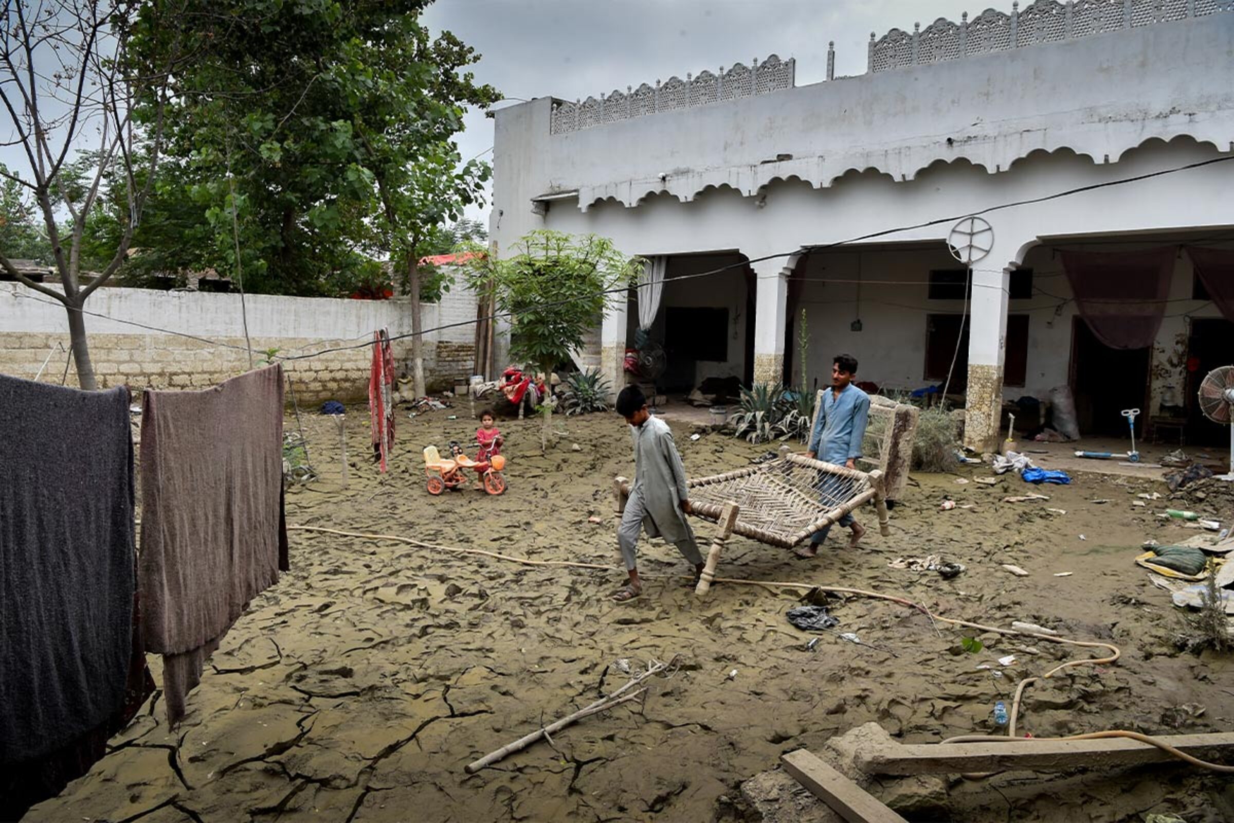 Zwei Kinder tragen Möbel aus einem Haus in Pakistan