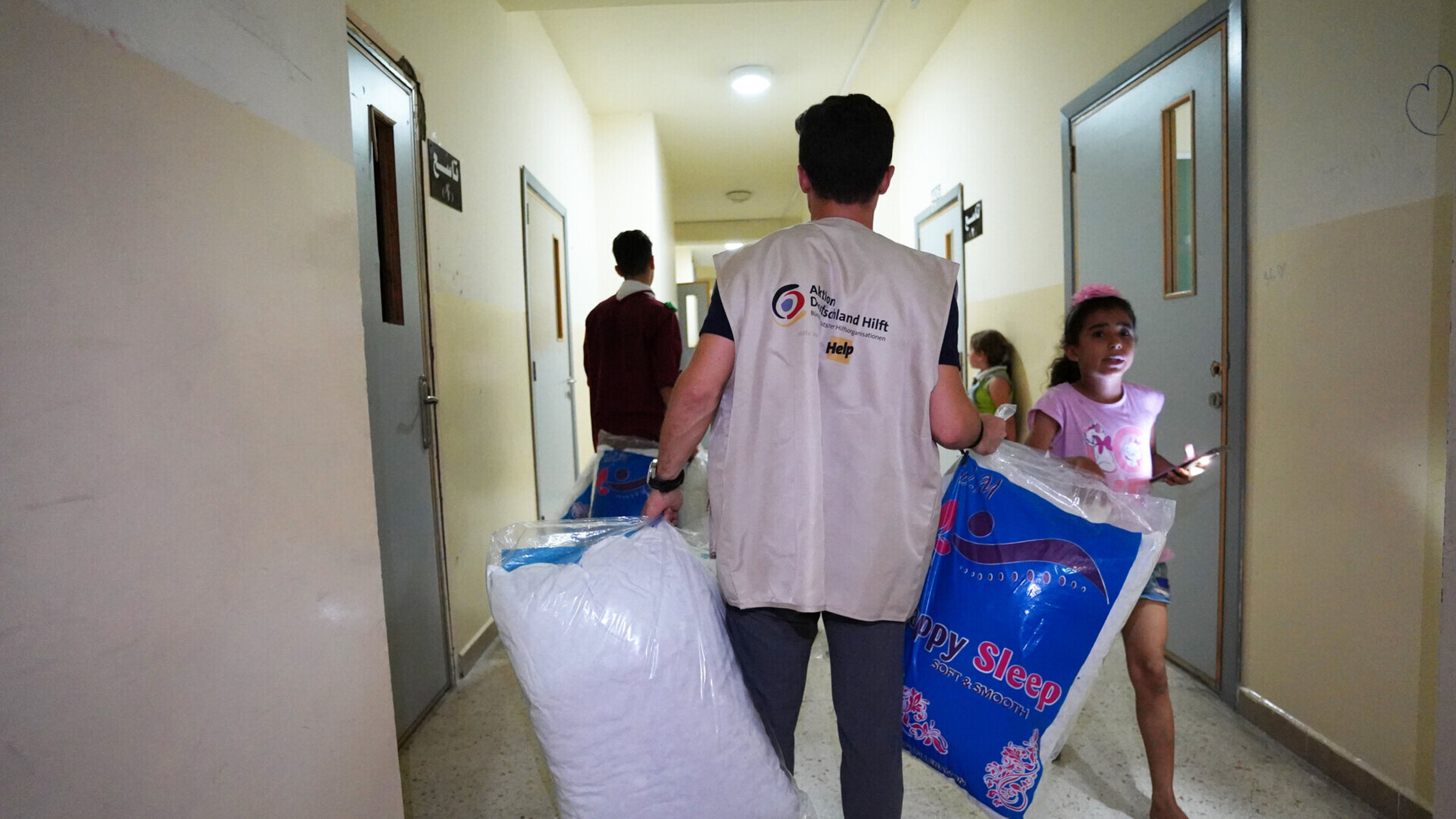 Ein humanitärer Helfer trägt Kissen in eine Notunterkunft