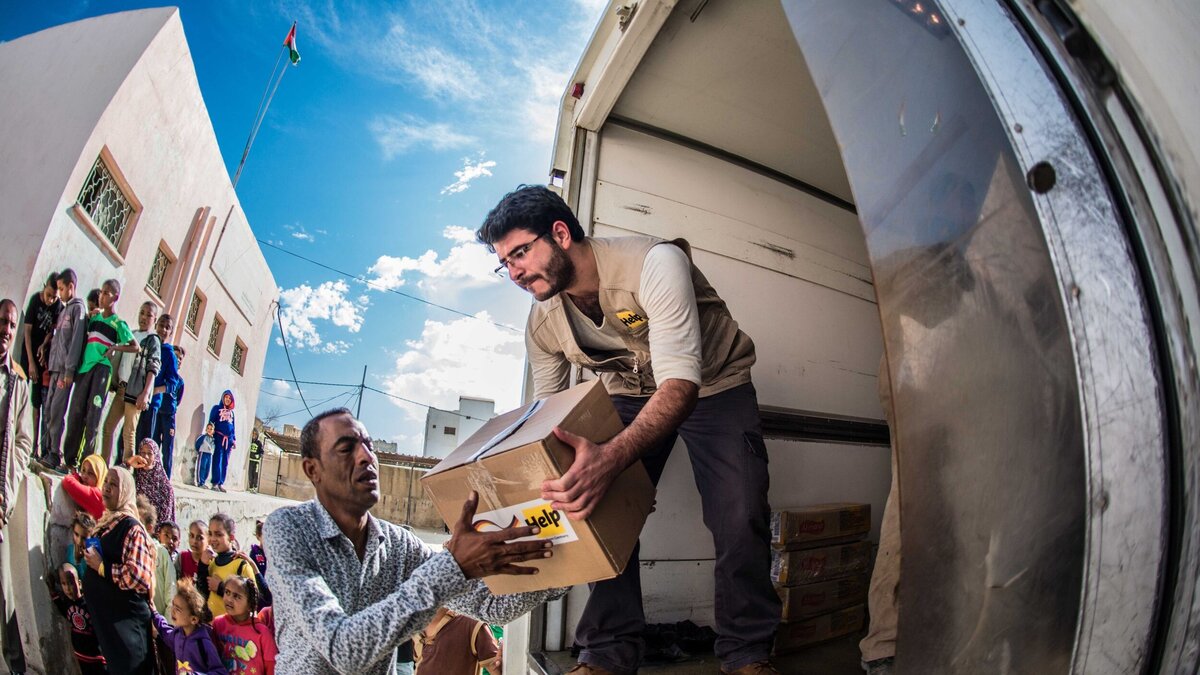 Humanitäre Hilfe: Verteilung von Hilfsgütern Ein humanitärer Helfer verteilt Hilfspakete an Betroffene