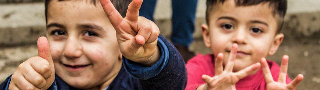 Zwei kleine Jungen machen das Peace-Zeichen und den Daumen nach oben