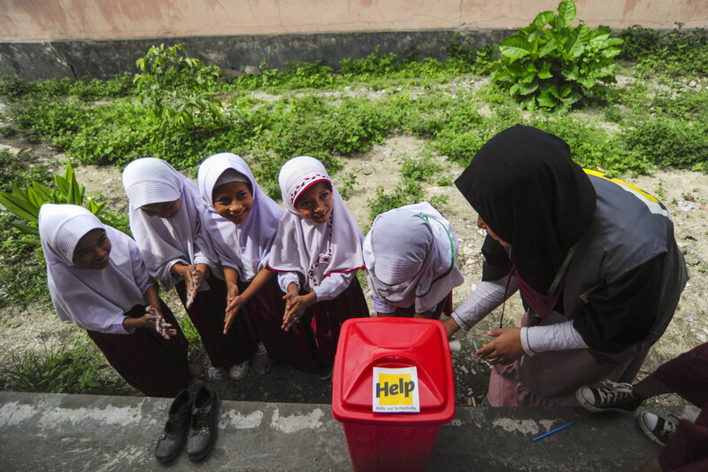 Eine Help-Mitarbeiterin zeigt indonesischen Kindern, wie sie sich mit gründlichem Händewaschen vor Krankheiten schützen können.