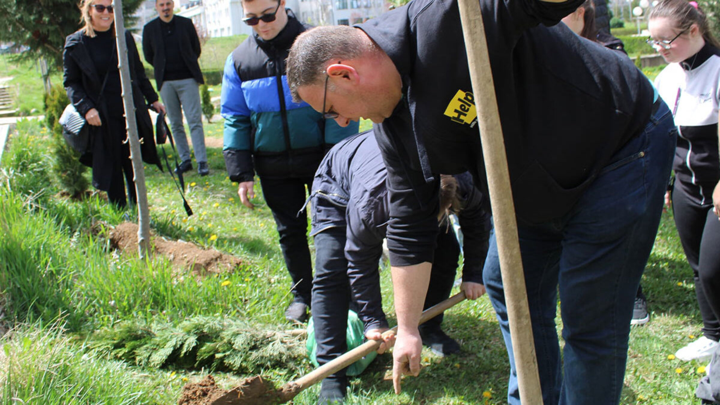 Help-Mitarbeiter und Kinder pflanzen einen Baum
