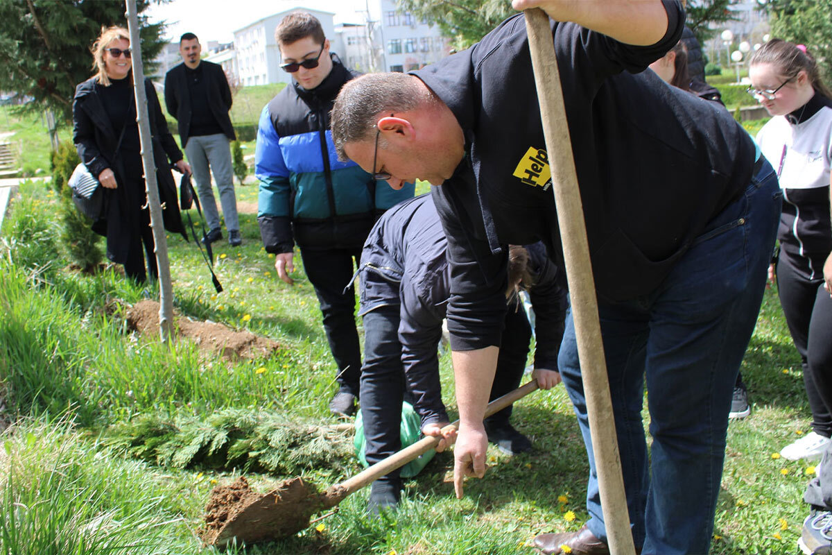 Help-Mitarbeiter und Kinder pflanzen einen Baum